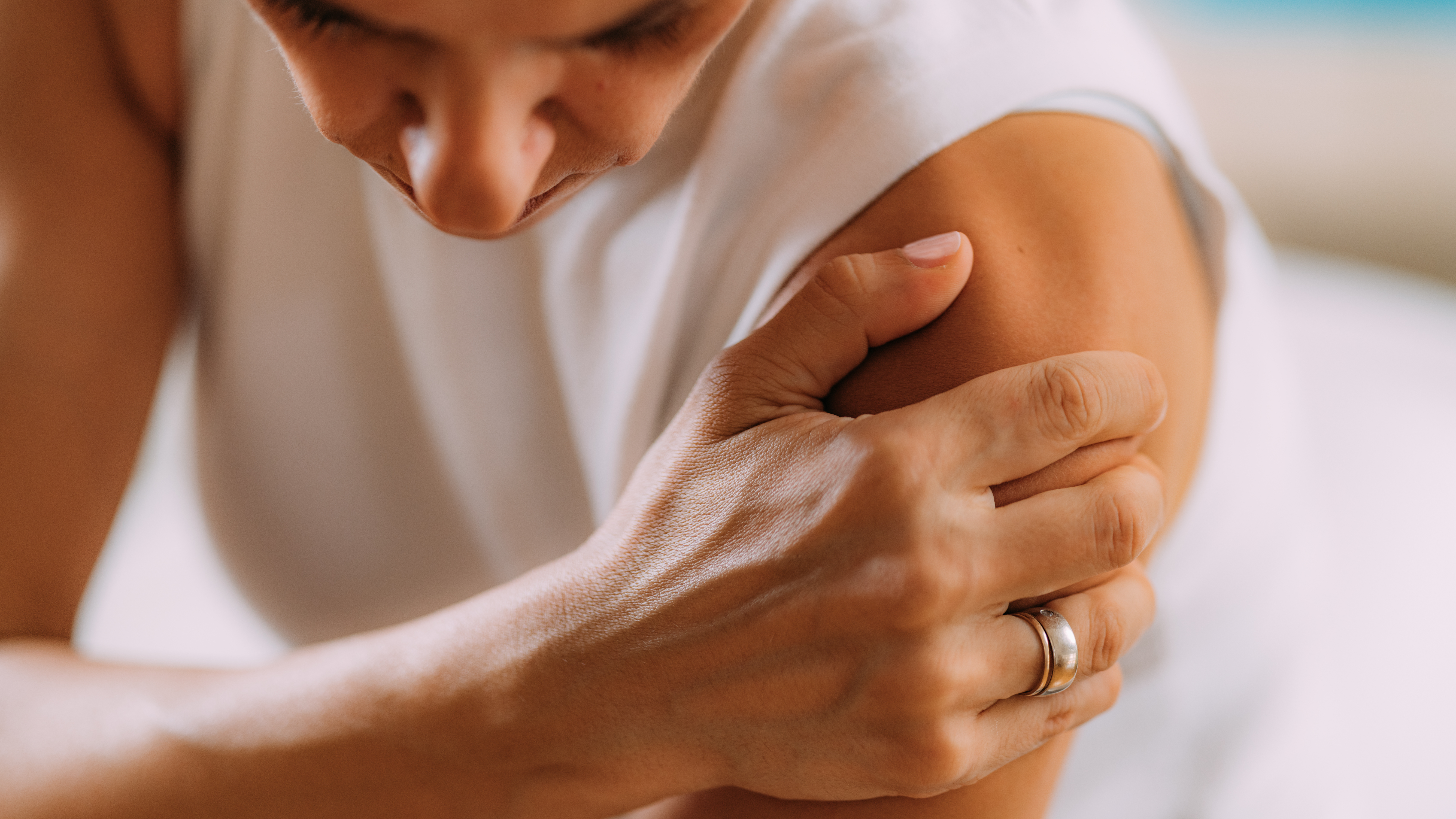 Individual experiencing shoulder discomfort and restricted movement, a common symptom of frozen shoulder in midlife women.